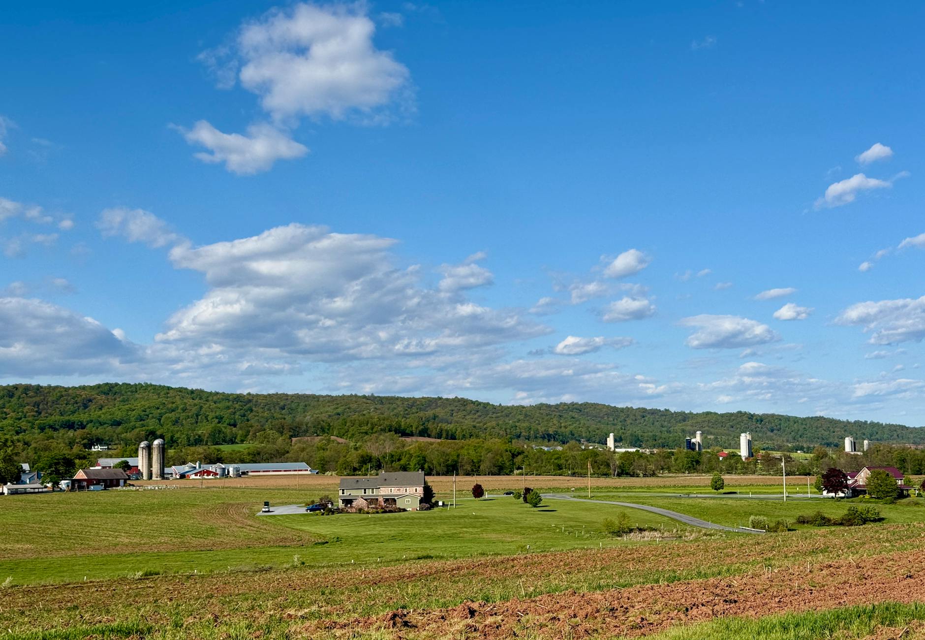 A picturesque view of Pennsylvania farmland under a clear blue sky with rolling hills.