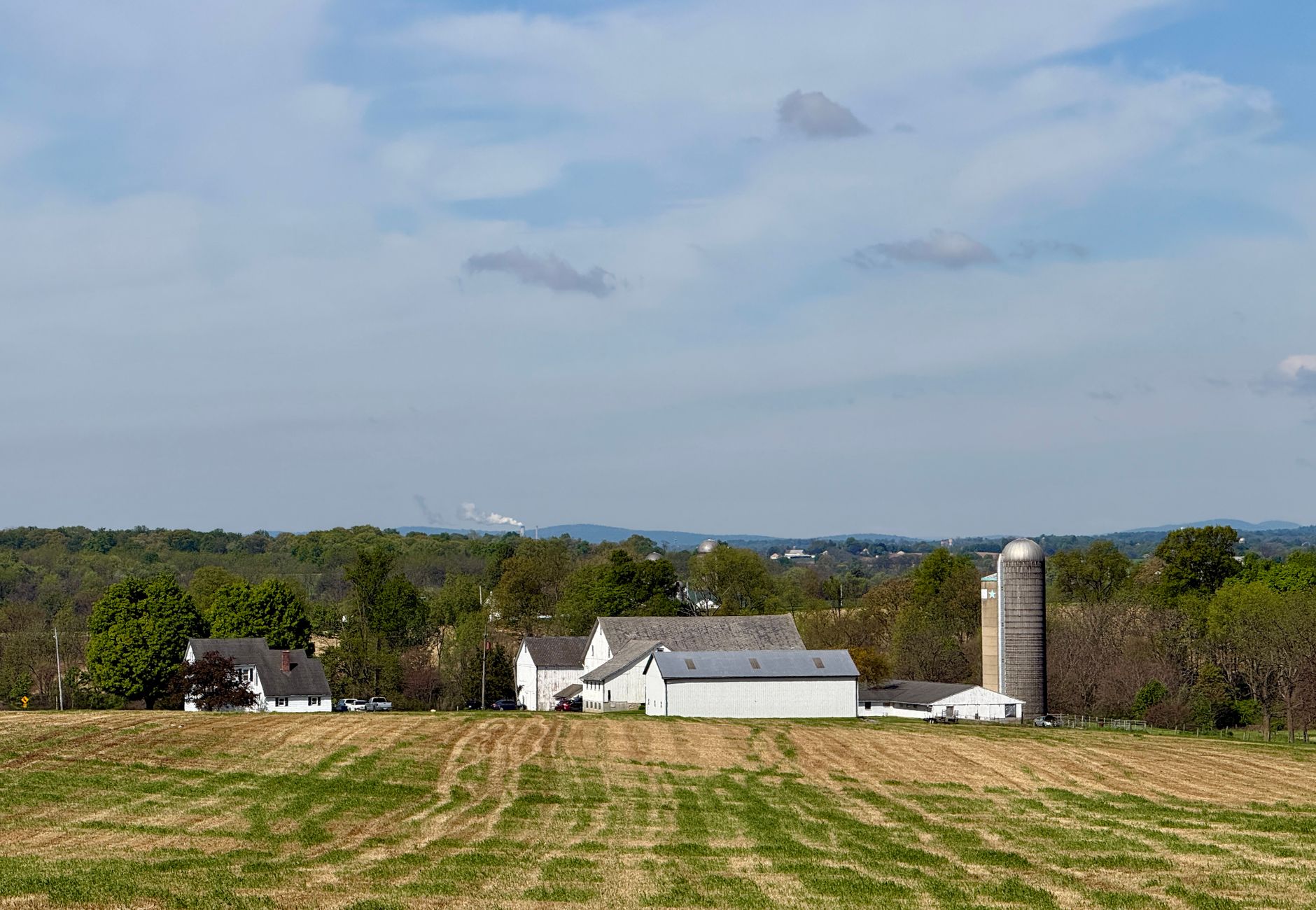 A scenic rural farm landscape with silos and barns in Pennsylvania under a blue sky.