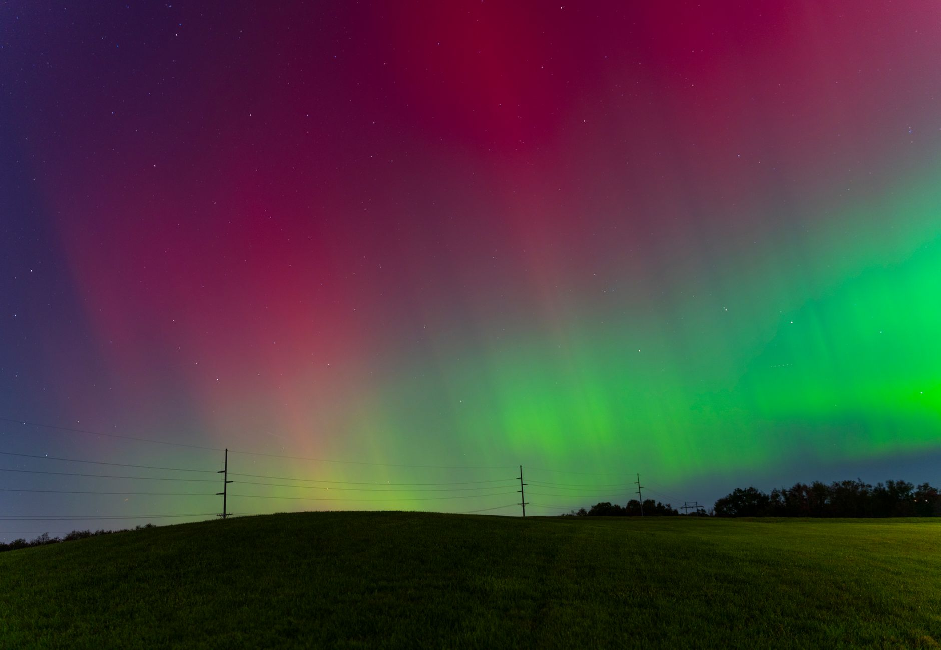 Vivid aurora borealis displaying colors over a tranquil field in Cranberry Township.